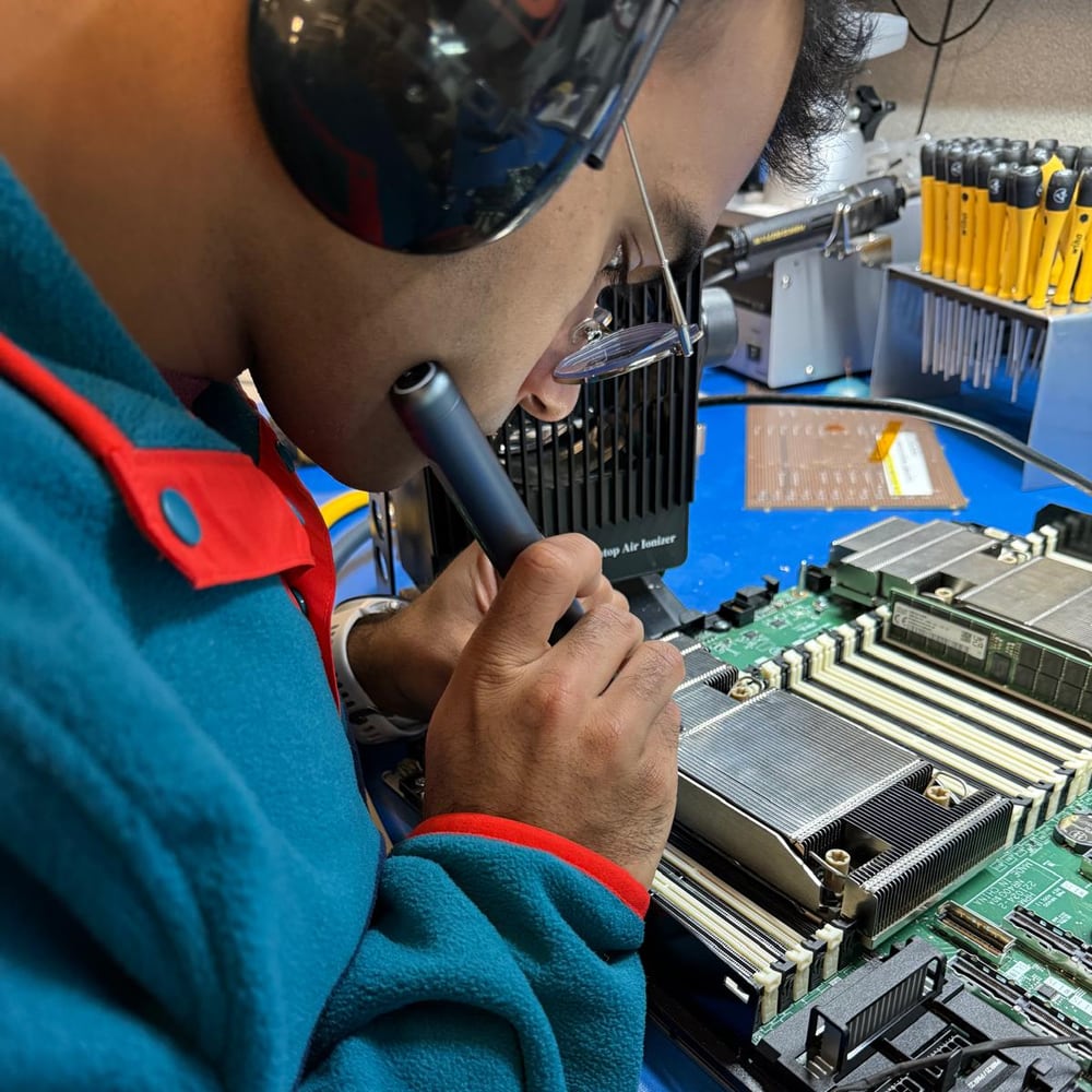 Manu at an ESD bench examining a server board through a magnifier probe